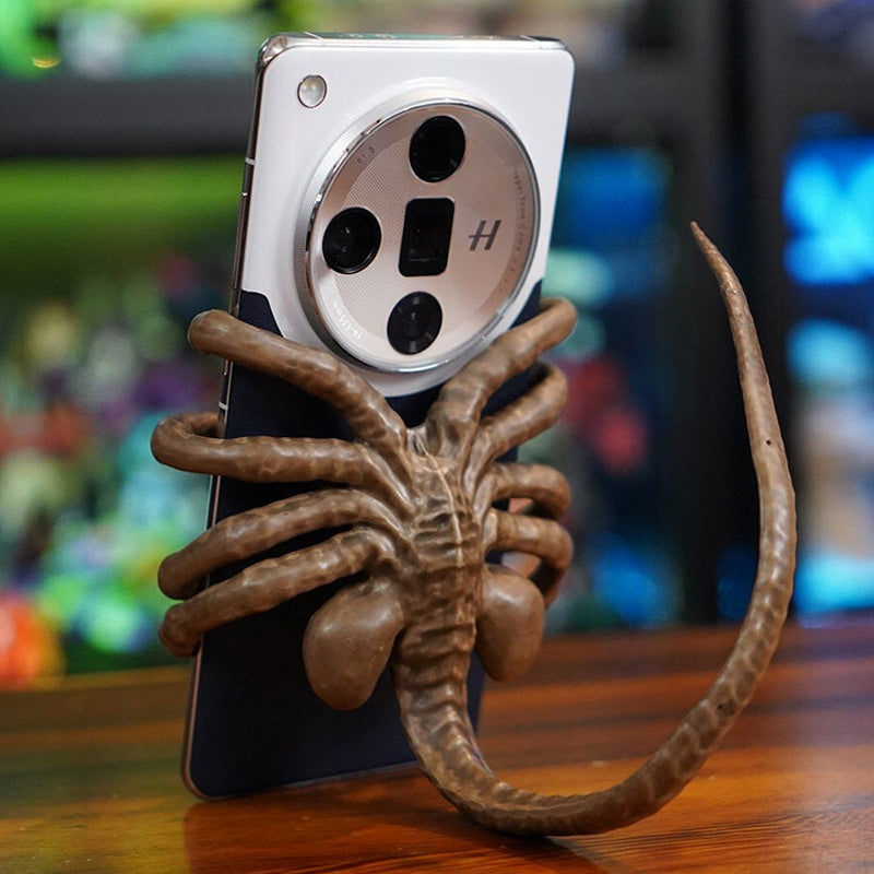Alienformad telefonhållare i grön harts, passar alla smartphones; justerbar svans för stabilitet. Perfekt som present.