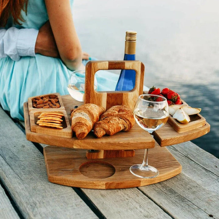 "Bärbart trä picknickbord med flaskhållare och matceller, perfekt för vin och snacks utomhus, naturfärgat och kompakt."