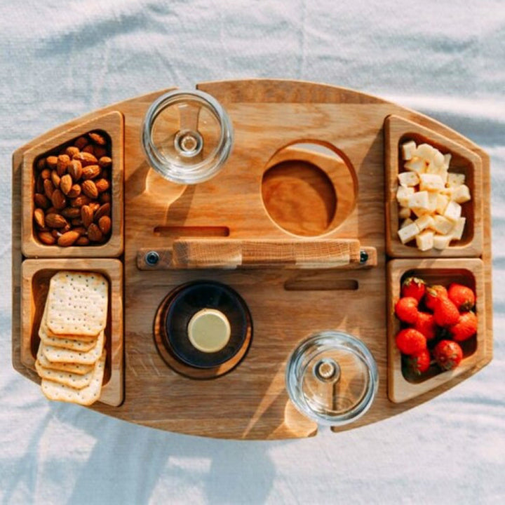 "Bärbart trä picknickbord med flaskhållare och matceller, perfekt för vin och snacks utomhus, naturfärgat och kompakt."