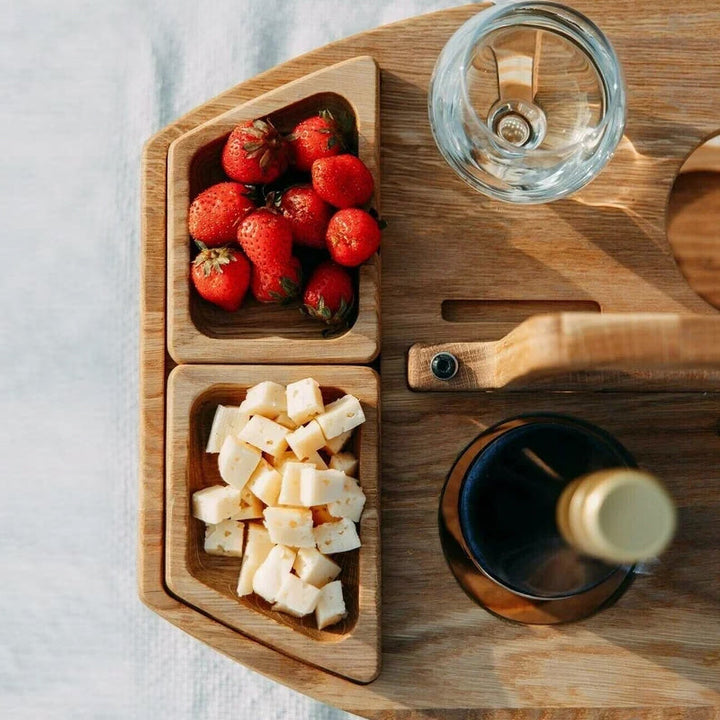 "Bärbart trä picknickbord med flaskhållare och matceller, perfekt för vin och snacks utomhus, naturfärgat och kompakt."