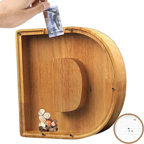 "Barn håller träbokstavs-spargris med glaspanel och bokstavsdesign, perfekt för pedagogisk sparning och inredning."