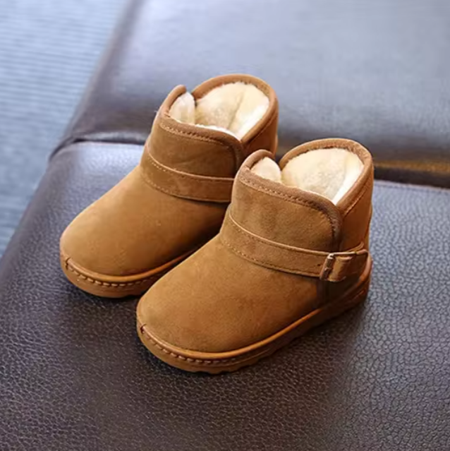 Flicka hoppar i snöhög med rosa, halkfria snöskor. Roliga och trygga vinterkängor för flickor.