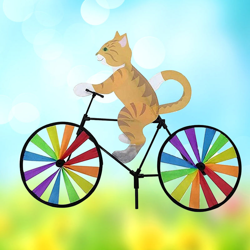 "Charmig katt på cykel vindsnurra, regnbågseffekt, färgglad trädgårdsdekoration, glittrande tygremsor i rörelse."