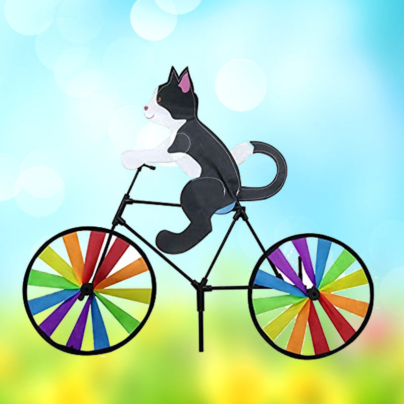 "Charmig katt på cykel vindsnurra, regnbågseffekt, färgglad trädgårdsdekoration, glittrande tygremsor i rörelse."