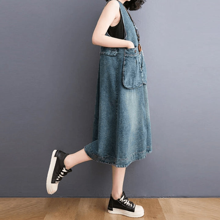 "Dam denim overallklänning med breda axelband och sidfickor, ärmlös design i jeansmaterial för stil och komfort."
