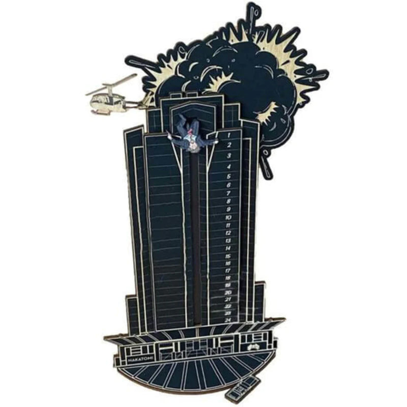 "Detaljerad trä Adventskalender med Die Hard-motiv, visar Hans Gruber faller från brunblå Nakatomi Plaza, roterbar design."