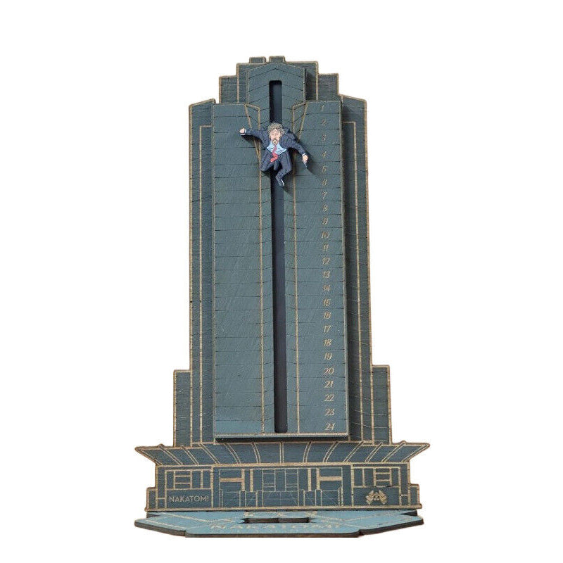 "Detaljerad trä Adventskalender med Die Hard-motiv, visar Hans Gruber faller från brunblå Nakatomi Plaza, roterbar design."