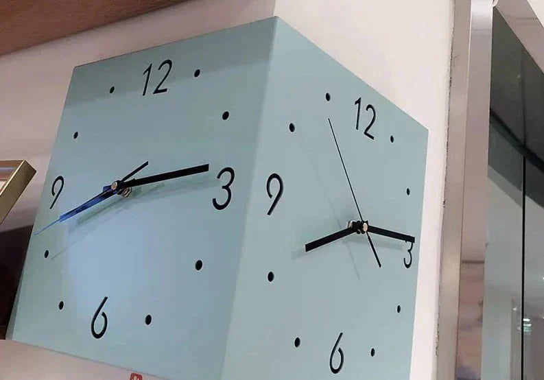 "Dubbel sidig hörnväggklocka med elegant metallisk yta, detaljerade siffror och visare. Klockans färg: grön, gul, rosa, vit."