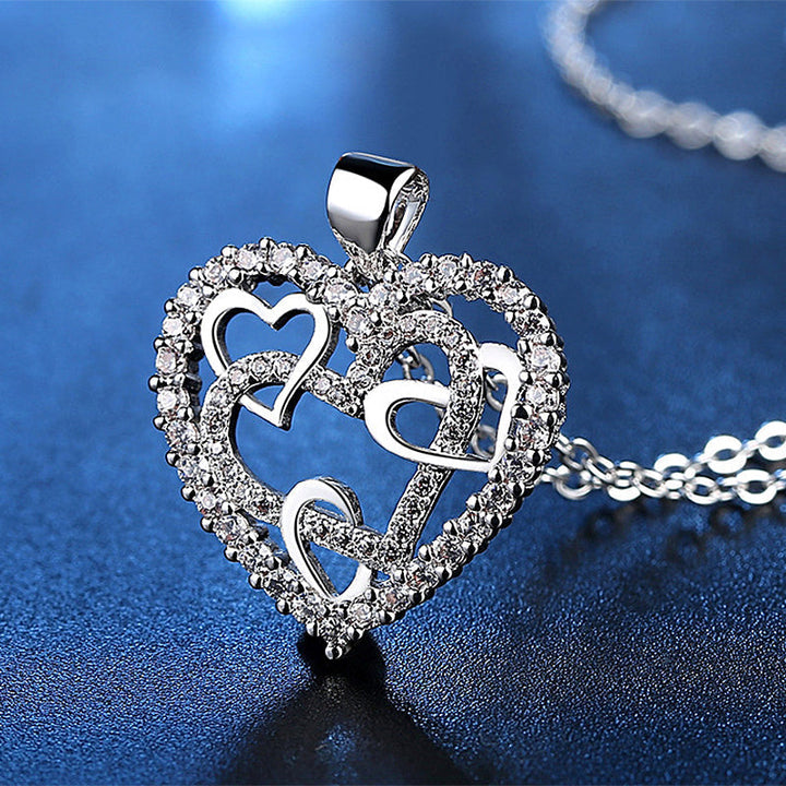 Dubbelhjärta halsband med gnistrande CZ-stenar, sammanlänkade hjärtan i roséguld och silver mot vit bakgrund.
