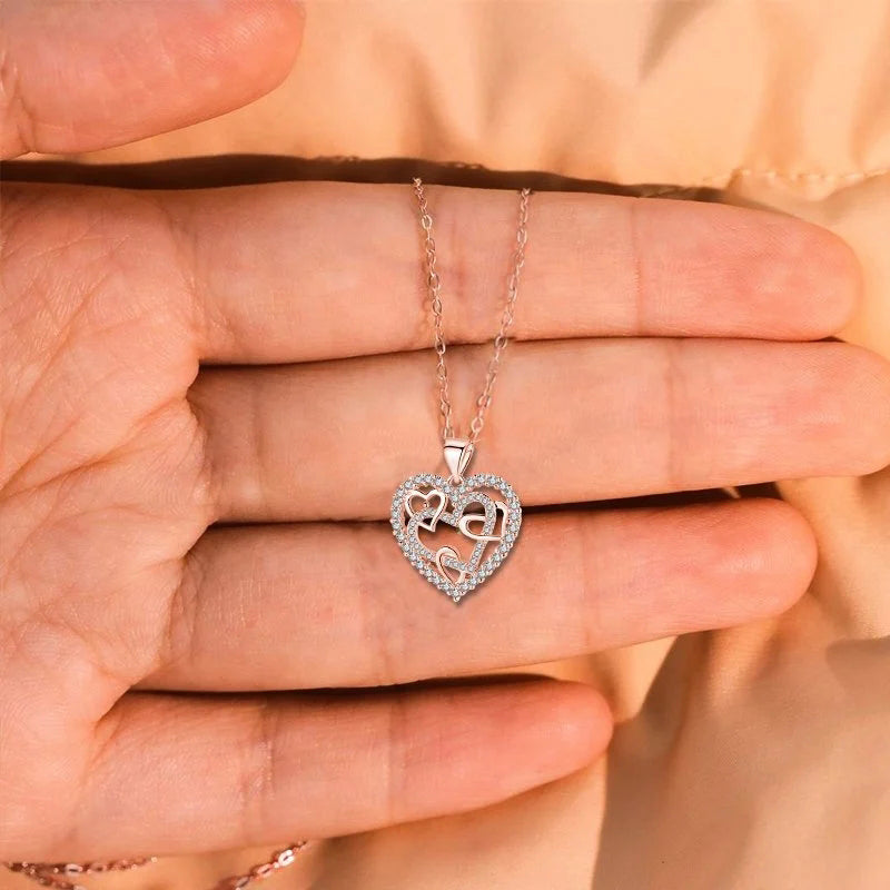 Dubbelhjärta halsband med gnistrande CZ-stenar, sammanlänkade hjärtan i roséguld och silver mot vit bakgrund.