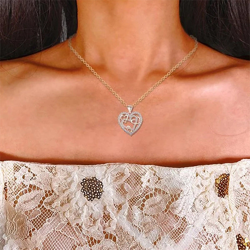 Dubbelhjärta halsband med gnistrande CZ-stenar, sammanlänkade hjärtan i roséguld och silver mot vit bakgrund.