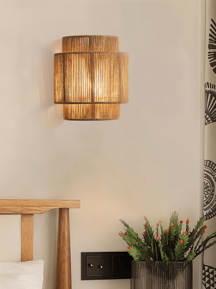 "Elegant boho hampavägglampa med rottingdetaljer, handgjord design som ger ett lugnande sken och naturlig atmosfär."