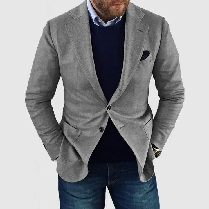 "Elegant herrblazer med tidlös design, mörkgrå färg, lång ärm, på modell, stilfullt sofistikerad look."