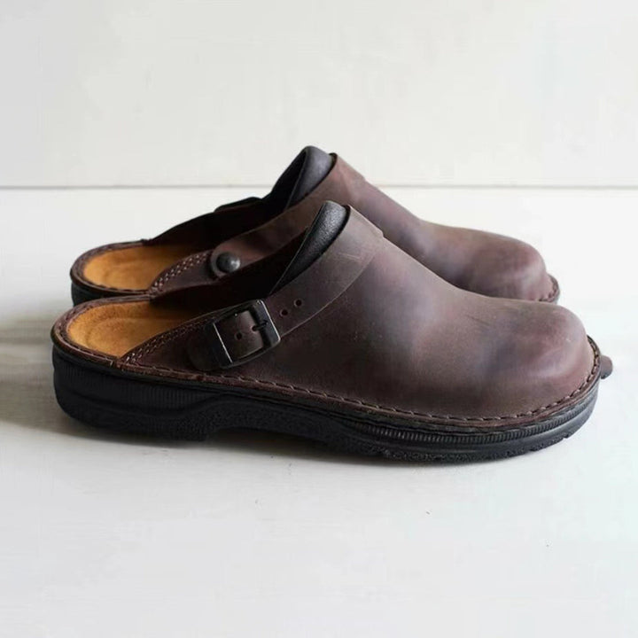 "Elegant herrskinntoffel i mörkbrun läder med halkfri sula, perfekt för värme och stil inomhus."