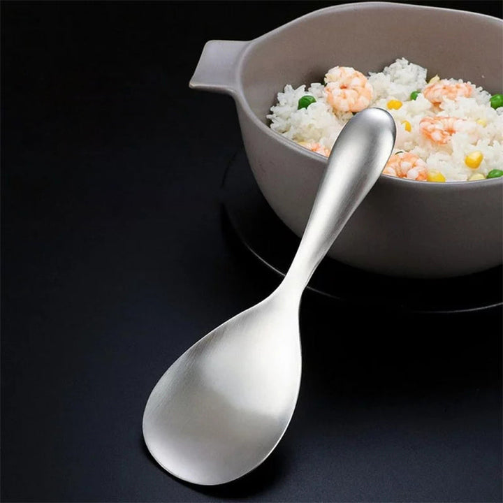 "Elegant och förtjockad non-stick rissked i rostfritt stål med ergonomiskt grepp, perfekt för kök och servering."