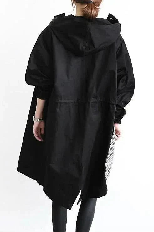 "Elegant och funktionell damregnkappa i modern oversized passform med stora knappar och stilfull huva, framifrån."