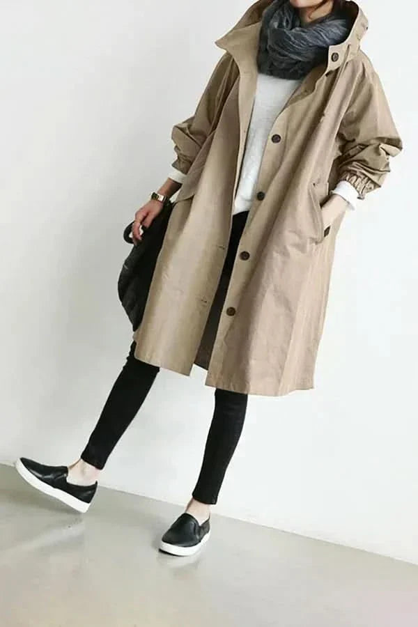 "Elegant och funktionell damregnkappa i modern oversized passform med stora knappar och stilfull huva, framifrån."