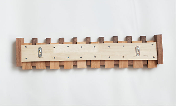"Elegant väggorganisatör i bokträ och valnöt med magnetiska krokar och pianotangentdesign. Optimera och stilrent för hemmet."