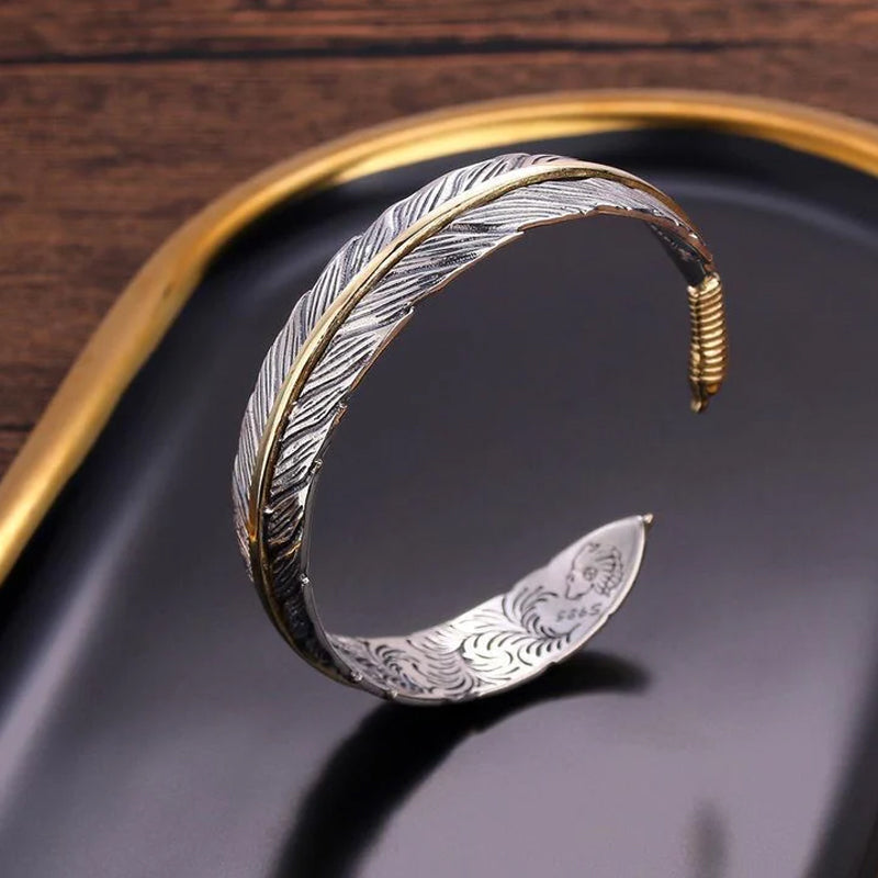 Elegant vintage fjäderarmband för damer i justerbart silver och guld, retro stil med symbolisk fjäderdetalj.