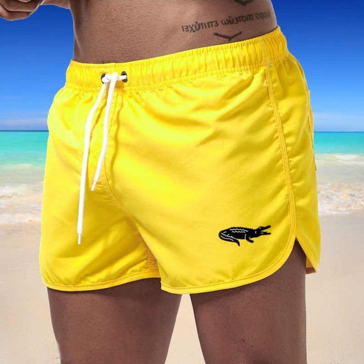 "Enfärgade herr badshorts med krokodilmönster i polyester, perfekt för sommar, tillgängliga i flera färger."