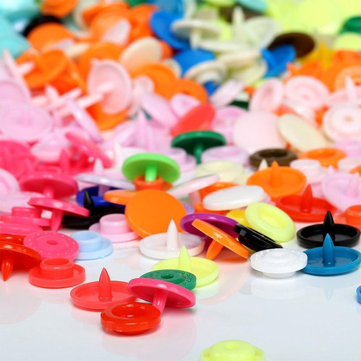 "Färgglada plasttryckknappar i DIY-paket med tång och tillbehör för hantverksprojekt, perfekt för kläder och hem."