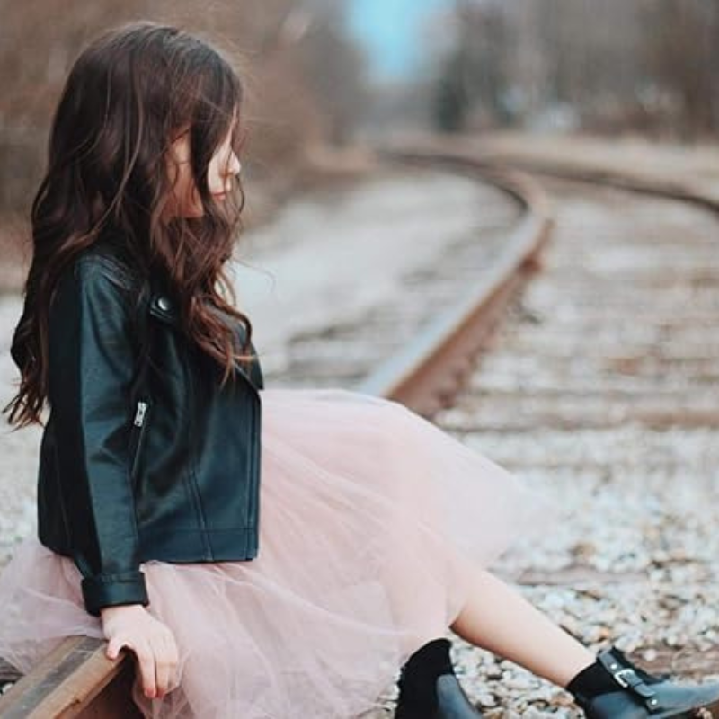 Närbild på midjebandet av flickklänningen i tyll, med subtila paljettdetaljer och en rosett.