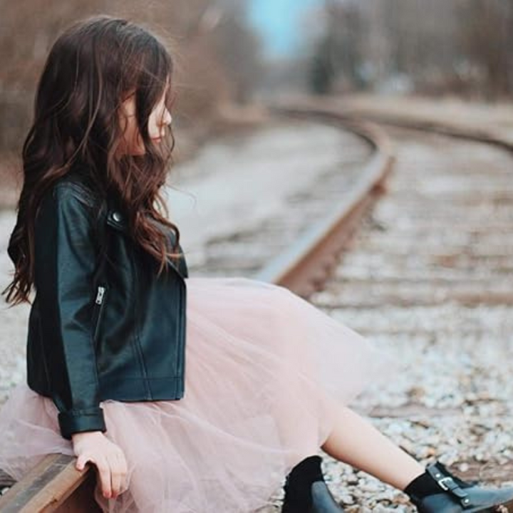 Närbild på midjebandet av flickklänningen i tyll, med subtila paljettdetaljer och en rosett.