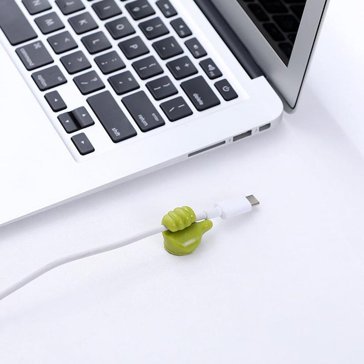 "Grön självhäftande Tumme Upp kabelhållare på slät yta, effektivt organiserar kablar, passar dator- och USB-kablar."