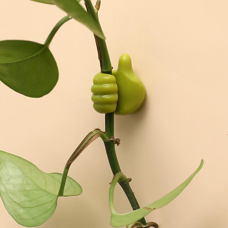 "Grön självhäftande Tumme Upp kabelhållare på slät yta, effektivt organiserar kablar, passar dator- och USB-kablar."