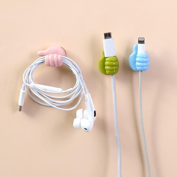 "Grön självhäftande Tumme Upp kabelhållare på slät yta, effektivt organiserar kablar, passar dator- och USB-kablar."