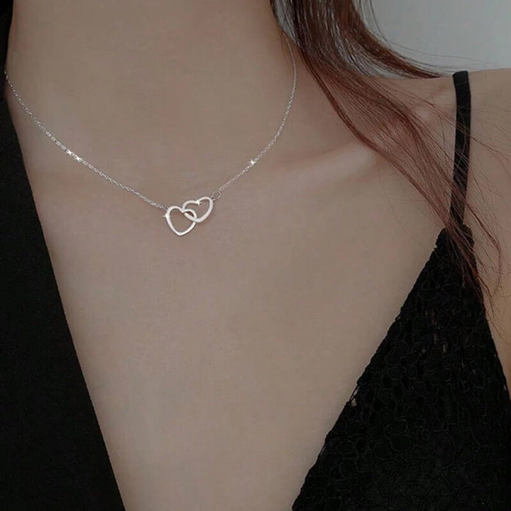 "Halsband för kvinnor med två sammanflätade hjärtan i titan stål, elegant romantisk design i guld, roséguld eller silver."