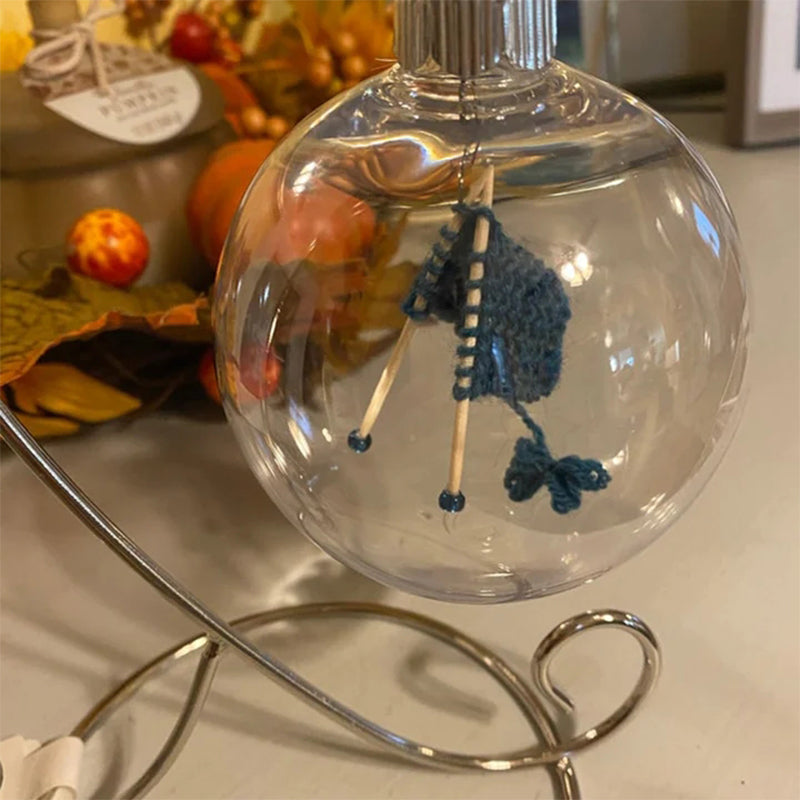 "Handgjord stickning juldekoration i glas, med akrylkula och charmig stickscen, perfekt för hem- och trädgårdsinredning."