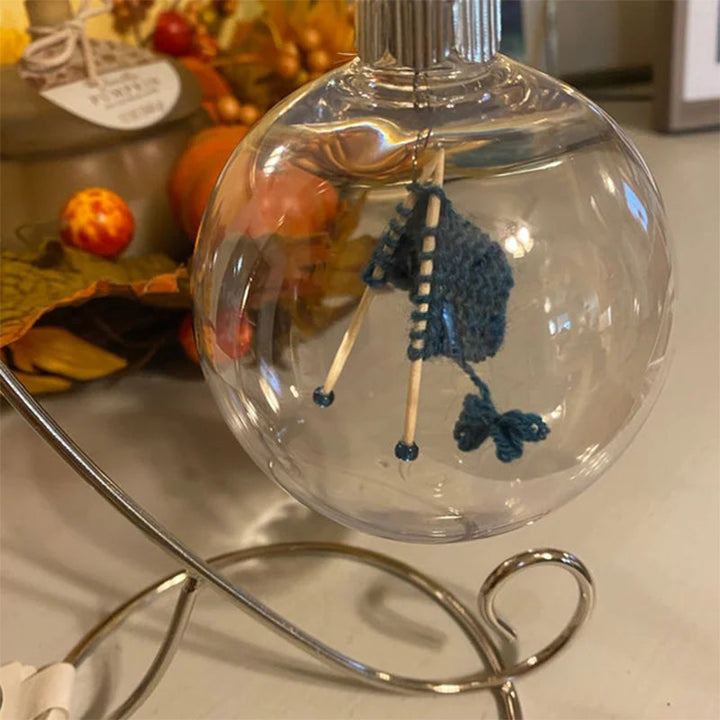 "Handgjord stickning juldekoration i glas, med akrylkula och charmig stickscen, perfekt för hem- och trädgårdsinredning."