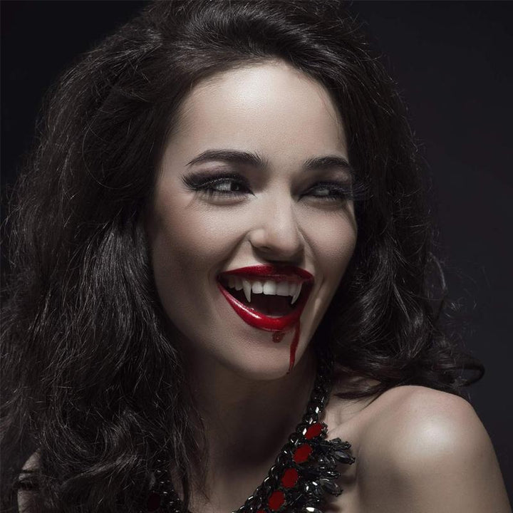 "Infällbara realistiska vampyrtänder halloween tillbehör, närbild med detaljrik ådring i vit silikon mot mörk bakgrund."