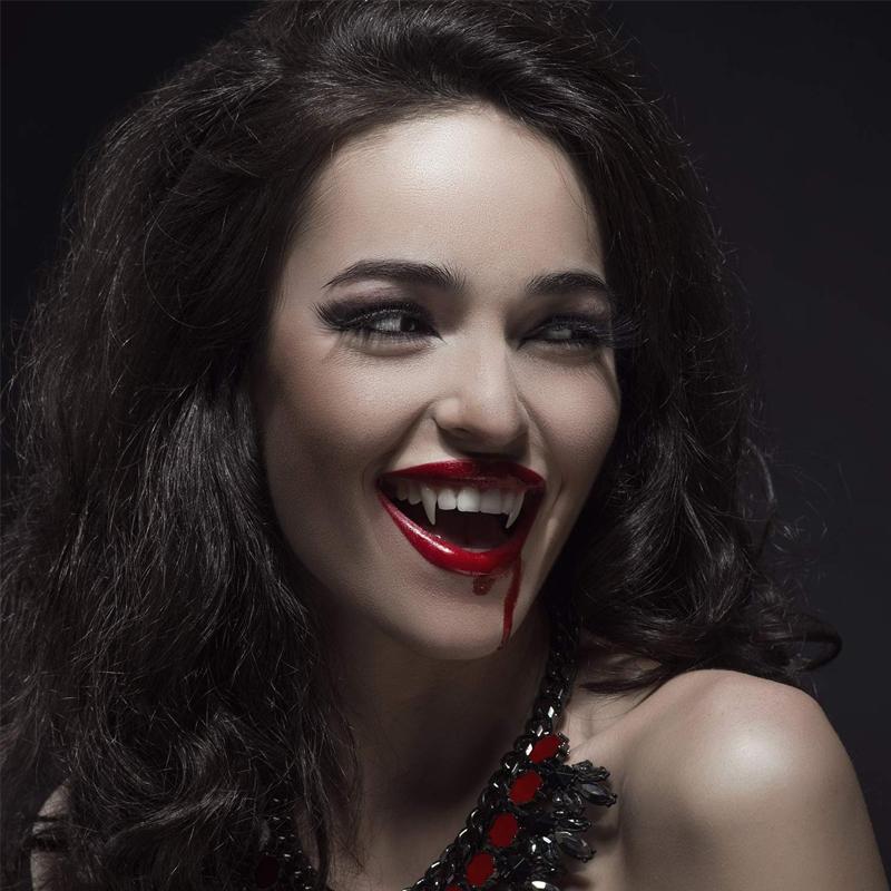 "Infällbara realistiska vampyrtänder halloween tillbehör, närbild med detaljrik ådring i vit silikon mot mörk bakgrund."