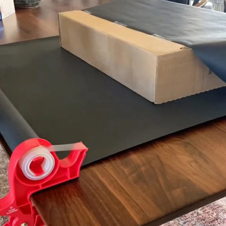 "Inslagningverktyg i röd och grå plast för presentinpackning, justerbar för olika pappersstorlekar."