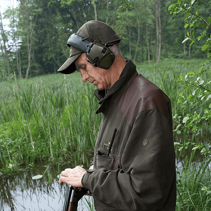 "Justerbar elektronisk hörselkåpa för skytte, grön och svart design, vadderat huvudband och lågprofil öronkåpor."