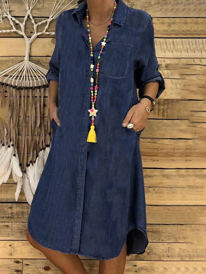 "Knälång denim skjortklänning med lång ärm, asymmetrisk fåll och bröstficka, perfekt för avslappnad stil."