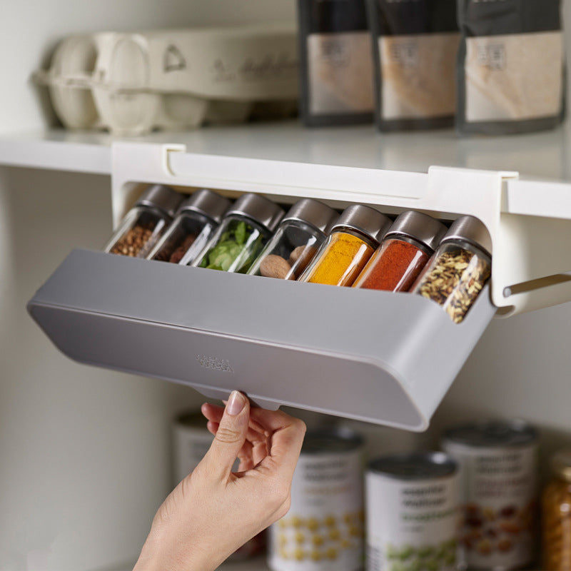 "Kryddorganisatör under hyllan med vit plastdesign, plats för sju kryddburkar, enkel installation i köket."