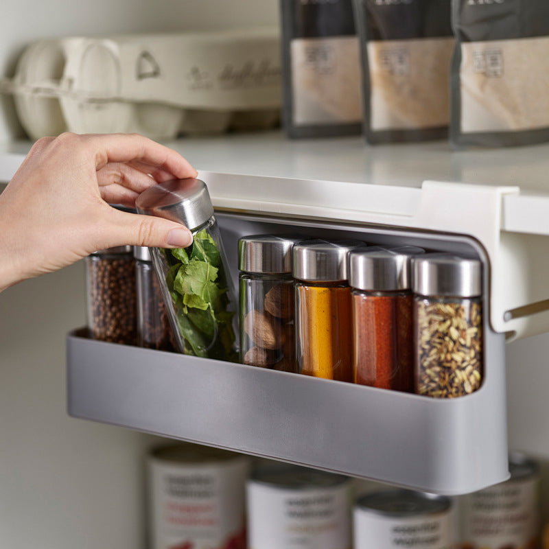 "Kryddorganisatör under hyllan med vit plastdesign, plats för sju kryddburkar, enkel installation i köket."