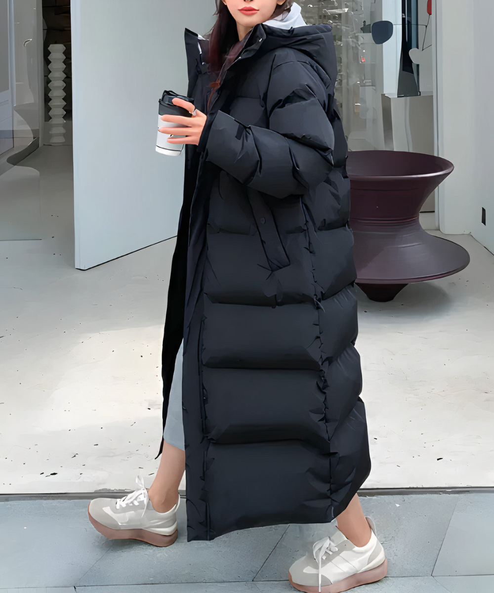 Lång damvinterjacka, fjäderfylld, vattentät, för kalla klimat. Elegant svart design, hög hals och justerbar passform.