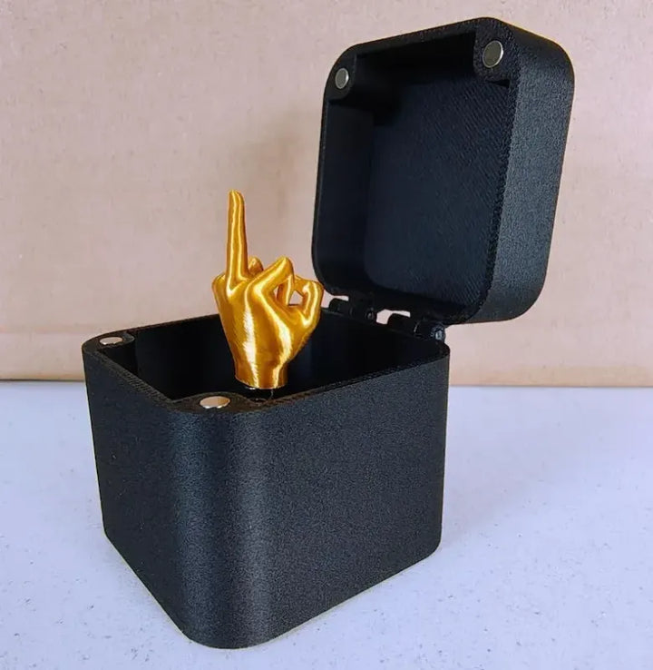 "Långfingret i en svart dosa med gulddetaljer, humoristisk present för honom och henne, hållbar PLA-plast, skämtsamma accesso