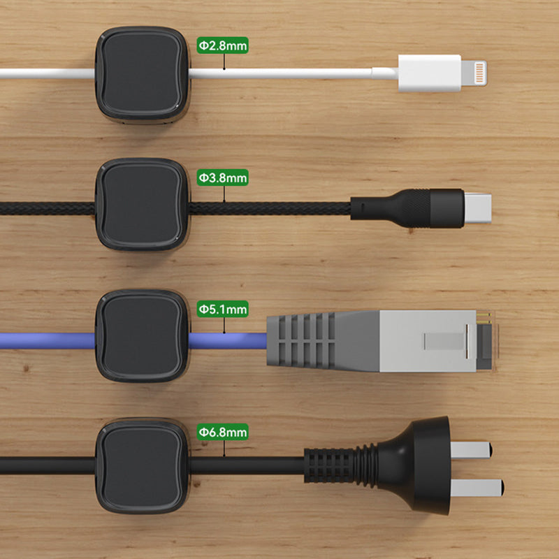 "Magnetisk kabelhållare håller kablar organiserade, stilren design i svart och vit, passar kablar upp till 7 mm."