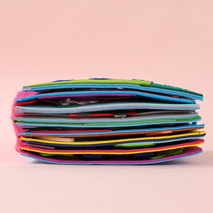 Barnhänder som utforskar en Montessori tygbok, fokuserar på en flik.