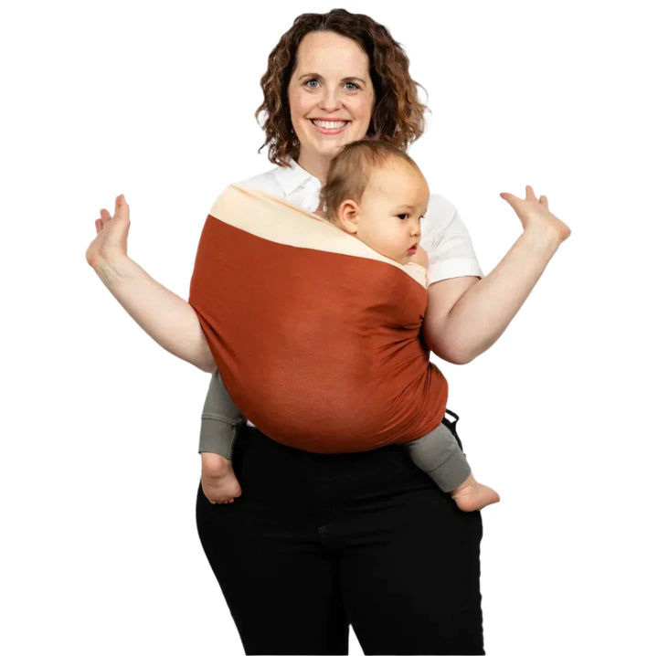 Nyföddsbärsele i mjuk orange färg, ergonomisk design för bekvämt babybärande, perfekt för föräldrar.