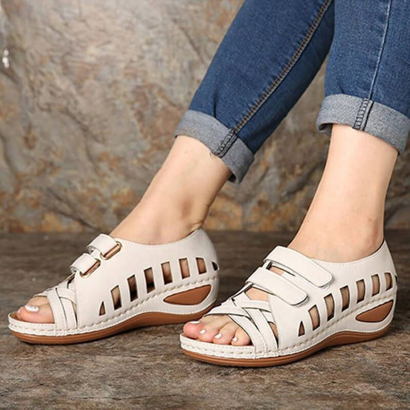 "Romerska dam sandaler med fiskmun, dekorativa skärningar och hög kilklack i elegant beige, framifrån."