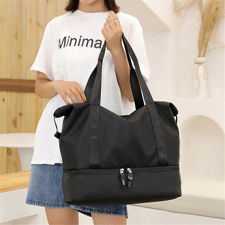 Detaljbild på handtagen och avtagbar axelrem på Catalina Deluxe väskan i svart.