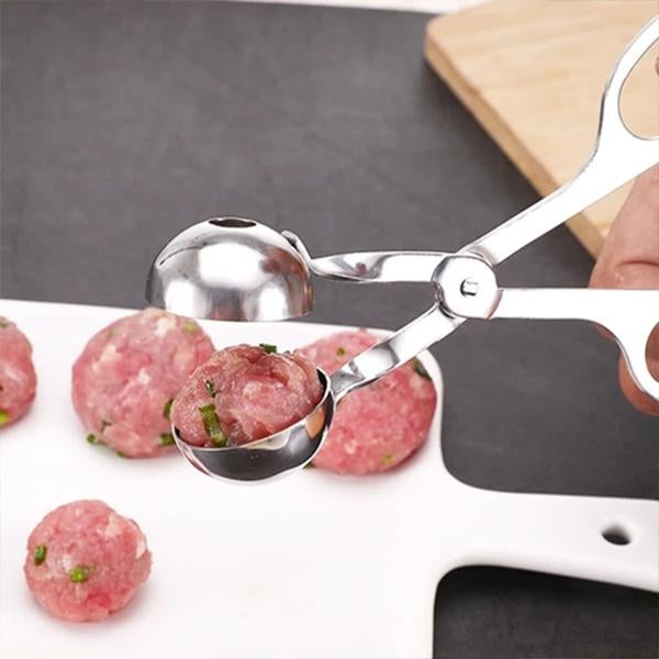 "Rostfri köttbulleskopa i silver, saxgrepp-design, idealisk för jämna köttbullar, meloner och kakbollar, i köksmiljö."