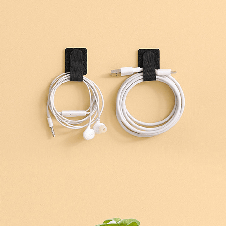 "Självhäftande kardborrearrangör för kablar, svart nylon, justerbar 28x90 mm, enkel installation på plana ytor."