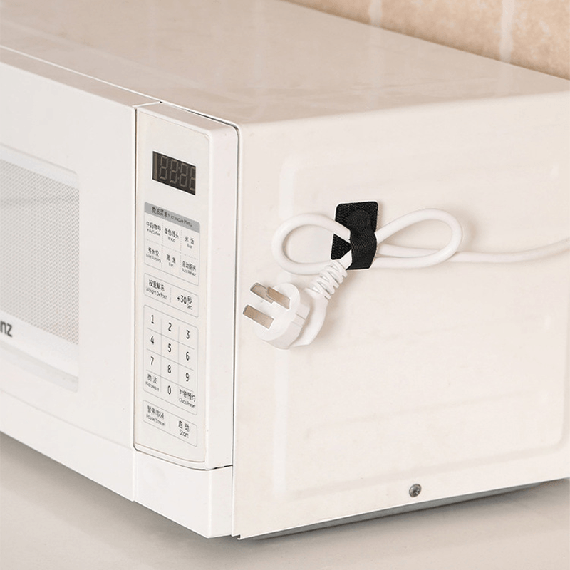 "Självhäftande kardborrearrangör för kablar, svart nylon, justerbar 28x90 mm, enkel installation på plana ytor."